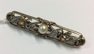 A pearl and yellow stone gold brooch with scroll d