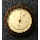 An oak carved wall barometer with silvered dial. E