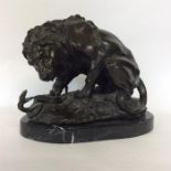 A large bronze figure of a fighting lion with snak