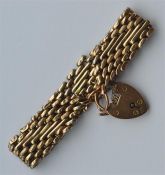 A 9 carat curb link gate bracelet with heart shape
