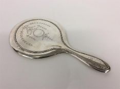 A silver back hand mirror decorated with swags and