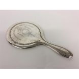 A silver back hand mirror decorated with swags and