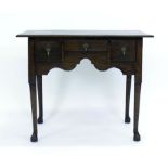A George II and later oak lowboy, the shaped frieze with three drawers,