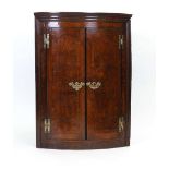 A George II pollard oak and crossbanded corner cabinet of bow fronted form, w.