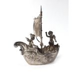 A novelty continental metalware boat sailed by a pair of putti, h.