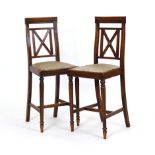 A pair of 19th century walnut and upholstered cello chairs on reeded legs joined by cross