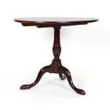 A George III mahogany tilt-top table, the oval surface on a turned column and tripod base, w.