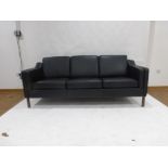 A 1970's black three seater sofa on square straight legs in the manner of Borge Mogensen