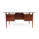 A 1970's teak desk with two pedestals suspended below and an arrangement of four drawers on