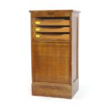 A 1940's oak tambour fronted cabinet on a plinth base, w.