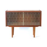 A 1970's teak cabinet with two glazed sliding doors on circular tapering legs, l.