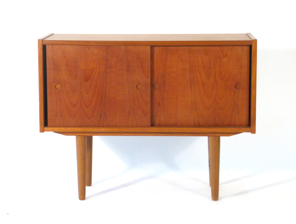 A 1970's teak cabinet with two solid sliding doors on circular tapering legs, l.