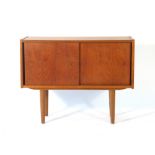 A 1970's teak cabinet with two solid sliding doors on circular tapering legs, l.