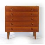 A 1960/70's teak chest of five drawers with integral circular handles on tapering legs, w.