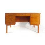 A 1960/70's teak desk with an arrangement of five drawers and one door on square straight legs, l.