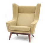 A 1950/60's upholstered wingback armchair on teak circular legs CONDITION REPORT: