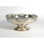 A silver shallow dish of circular form having a pierced shell design border above a flared foot,