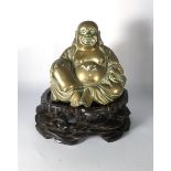 A brass figure modelled as a seated Buddha on a carved hardwood stand, h.