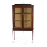 An Edwardian mahogany and glazed two door display cabinet with two shelves on a matching stand, w.