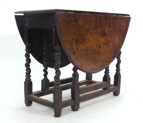 A 17th century and later oak gateleg dining table with an oval drop-leaf top on barley twist