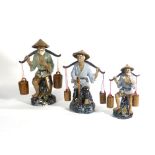 Three modern Chinese stoneware figures each modelled as a male figure carrying a yoke, max h.