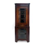 A late 18th century oak corner cabinet, the two glazed doors separated by a small drawer,