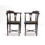 A pair of Edwardian mahogany and later upholstered corner armchairs with X-stretchers