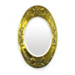 An Art Nouveau type brass wall mirror of oval form,