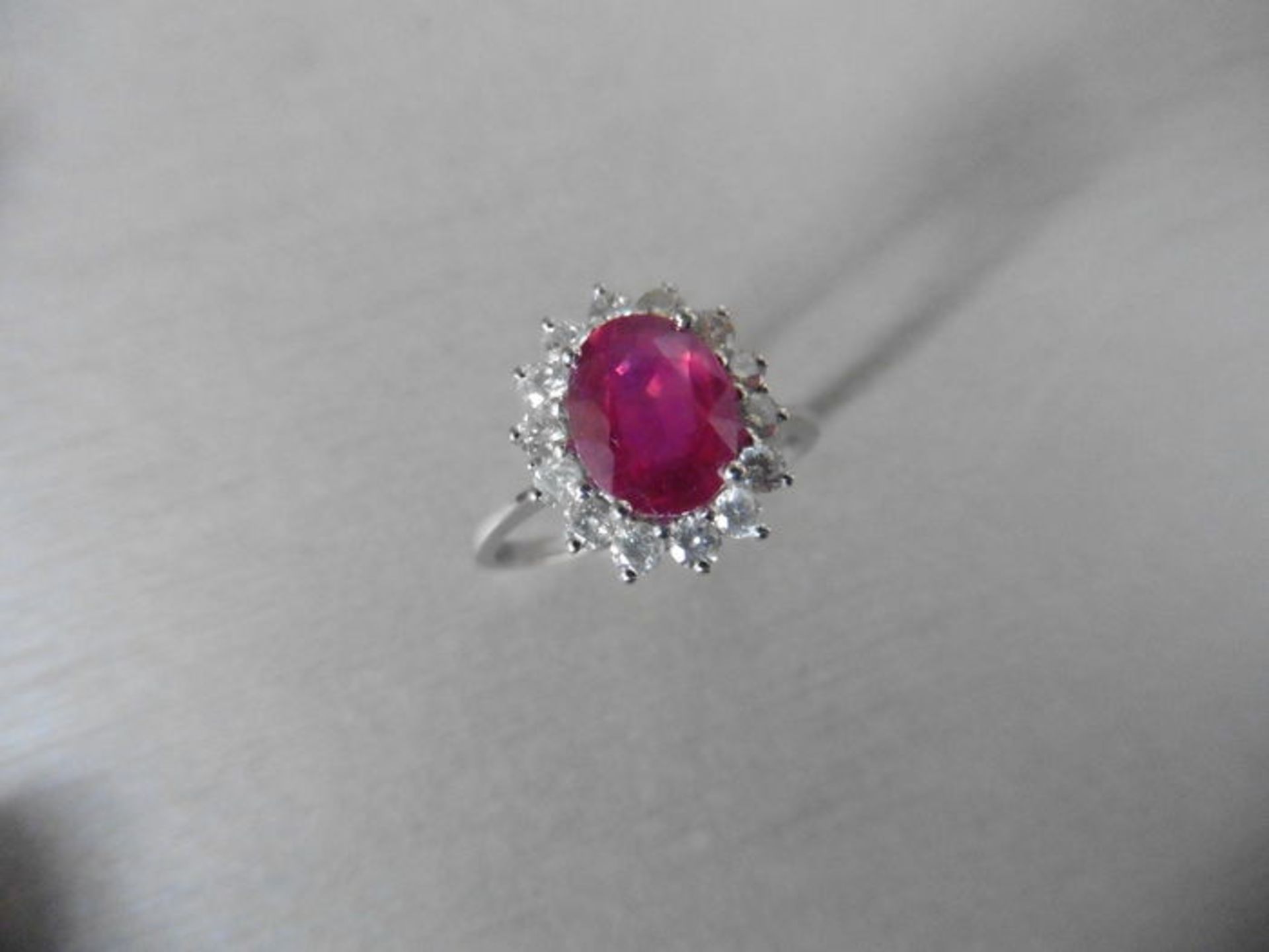 Ruby and diamond cluster style ring set in platinum. Oval cut ( glass filled ) ruby 2.50ct with 0.