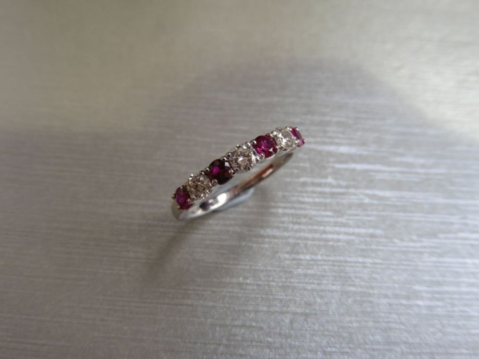 Ruby and diamond eternity band ring set in platinum. 4 round cut ( treated ) rubies and 3