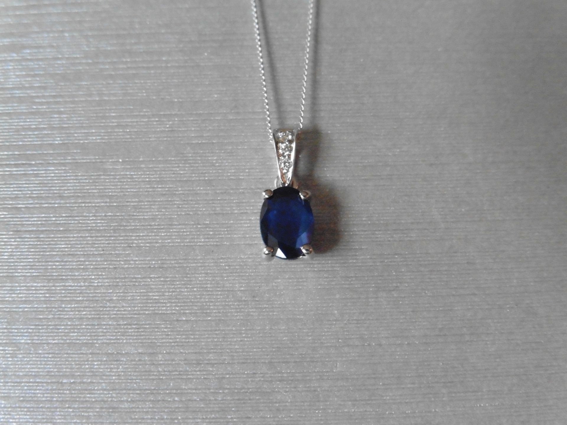 0.80ct Sapphire and diamond pendant. 7 x 5mm oval cut sapphire set in a four claw setting. The