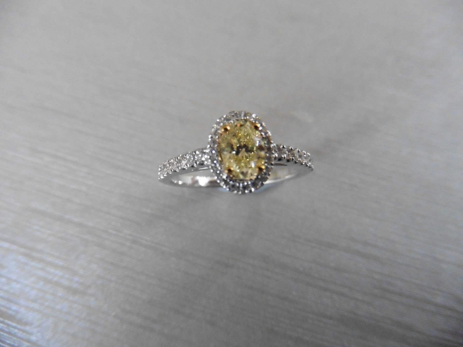 0.40ct yellow oval diamond set solitaire ring with a halo setting of brilliant cut diamonds, H