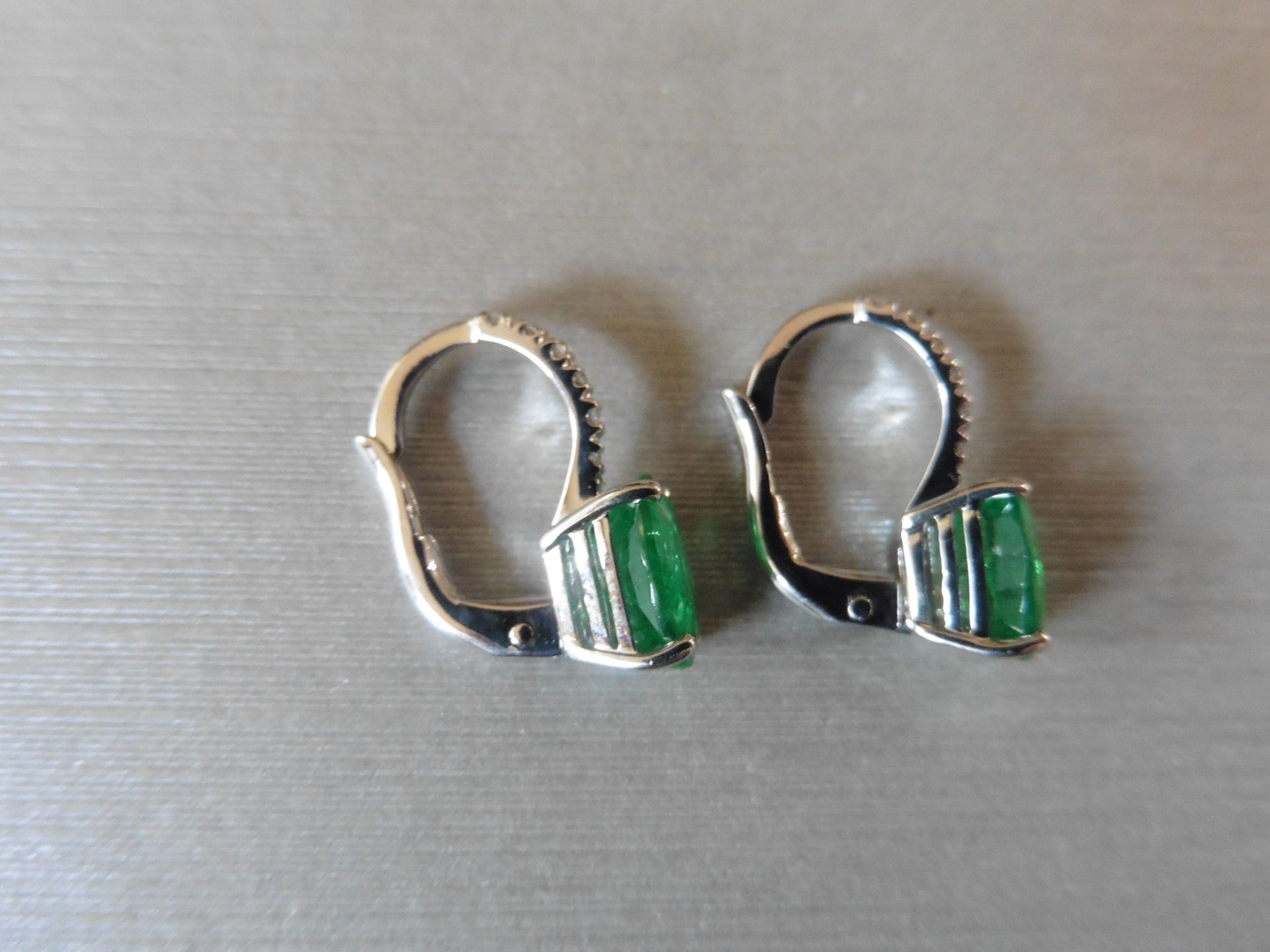 1.60ct emerald and diamond hoop style earrings. Each is set with a 7 x 5mm oval cut emerald with 6 - Image 3 of 4