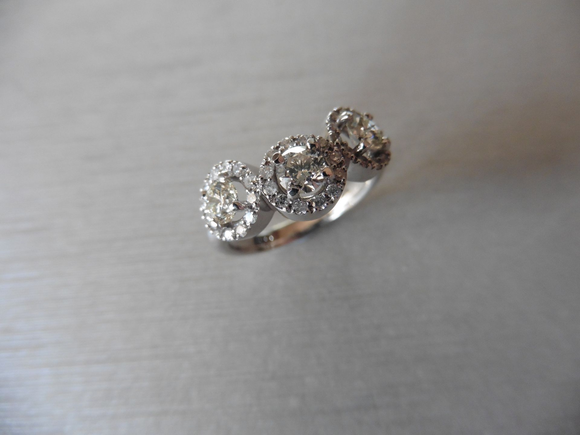 1.03ct diamond halo set trilogy style dress ring. Set with 3 centred brilliant cut diamonds, I