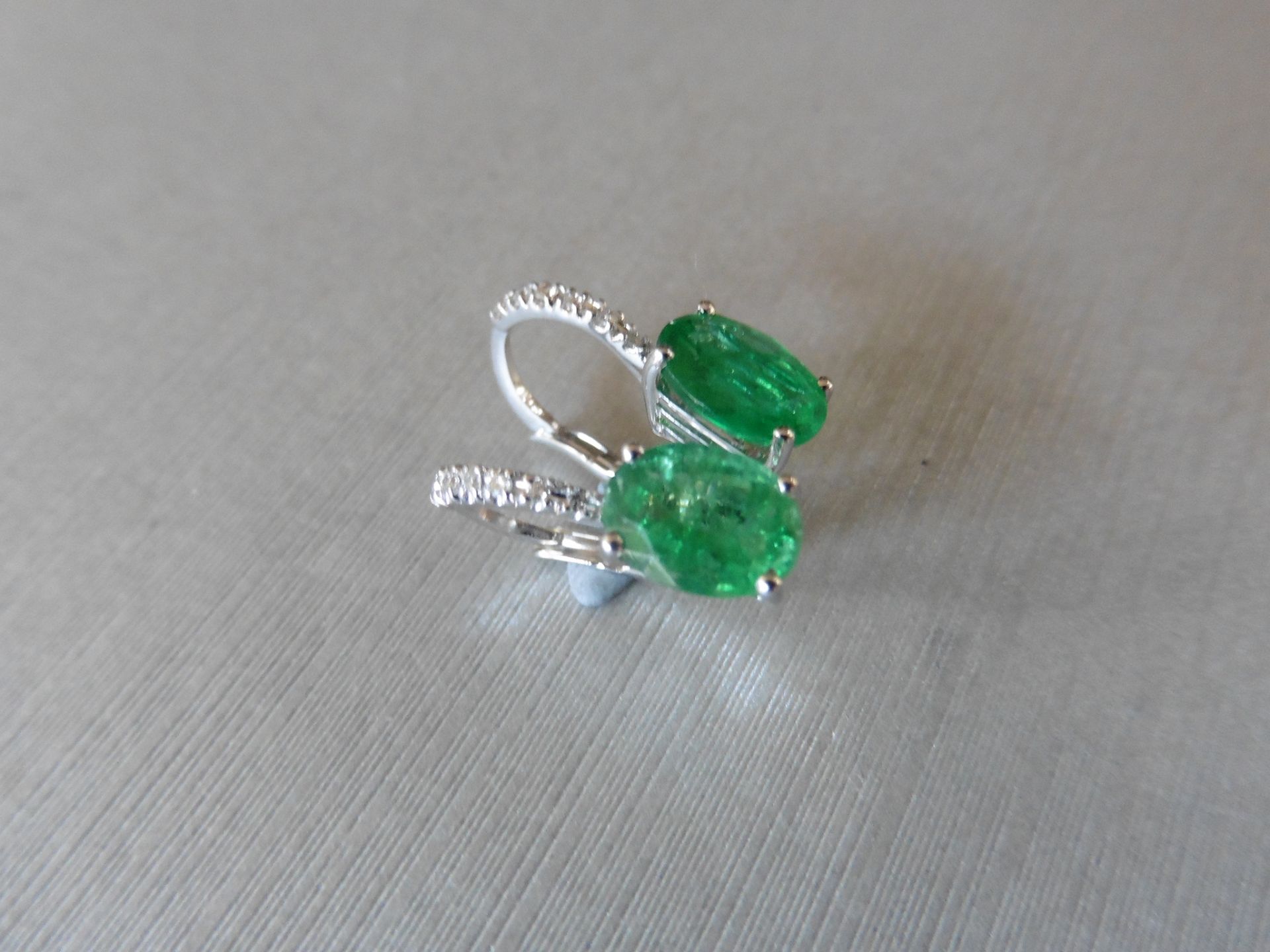 1.60ct emerald and diamond hoop style earrings. Each is set with a 7 x 5mm oval cut emerald with 6 - Image 2 of 4