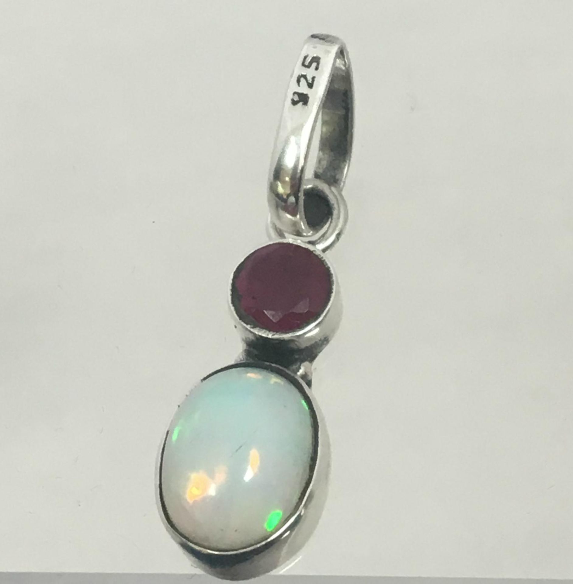 A 30mm drop gemstone pendant set with a cabochon cut opal (est. 2 carat) and a round cut faceted