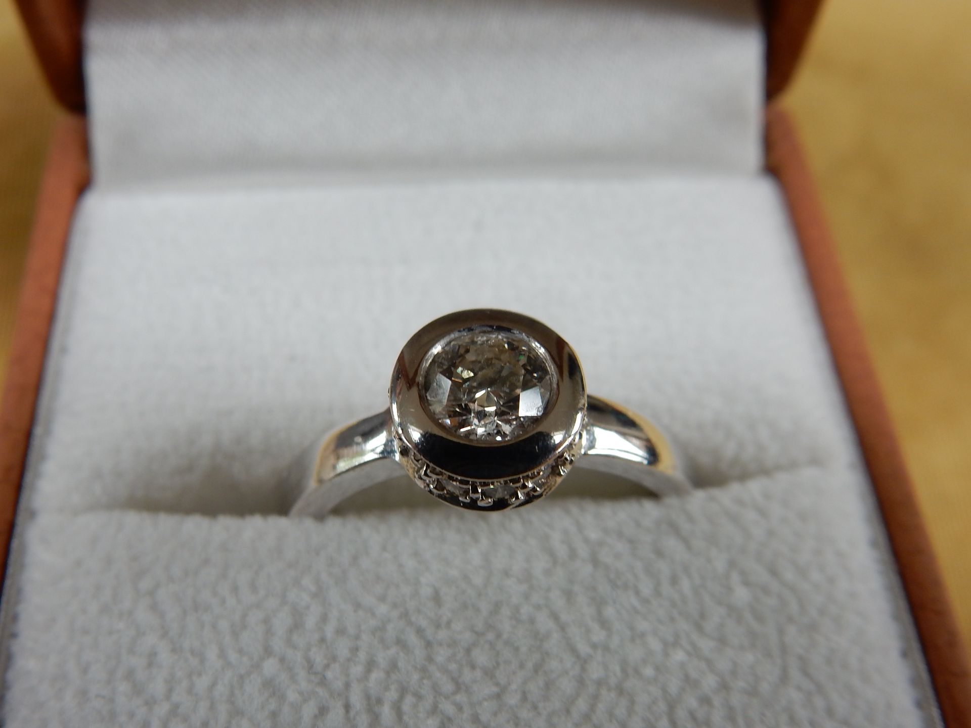 A 14 carat white gold single stone ring with diamonds set mount sides.