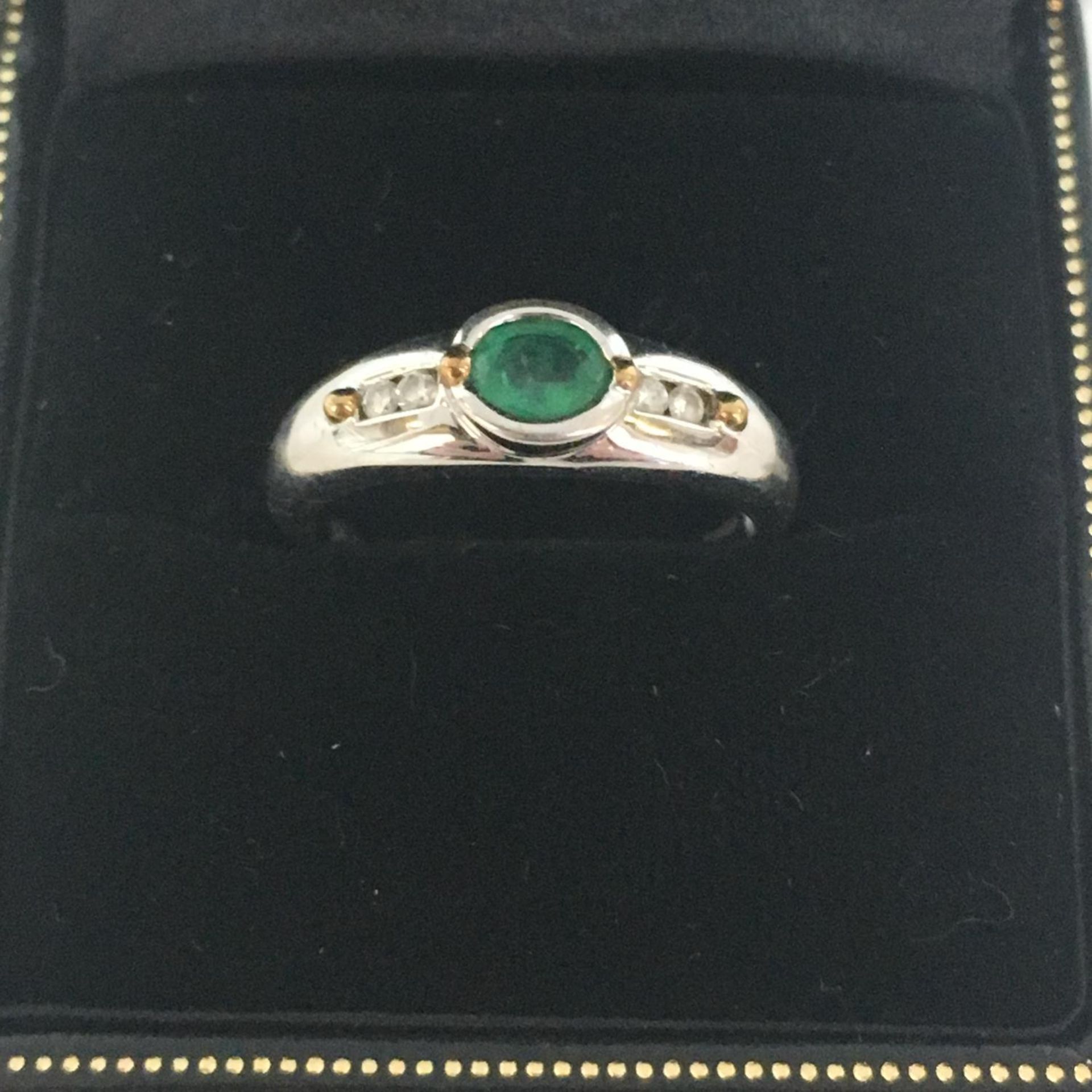 9CT WHITE GOLD AND EMERALD RING WITH DIAMONDS SET TO THE SHOULDERS. In box and size M. The hammer