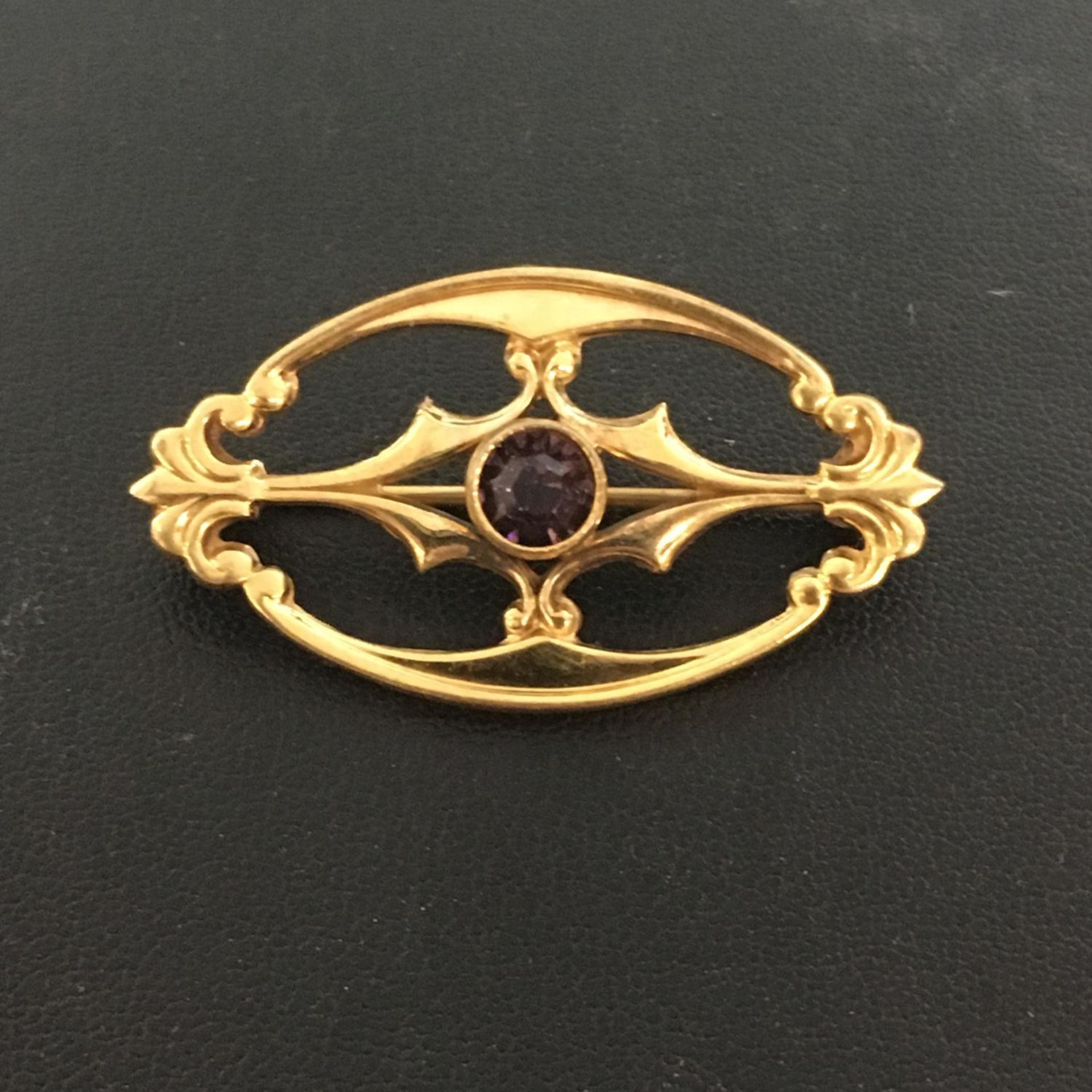 AMETHYST AND ROLLED GOLD BAR BROOCH. Oval shape with pretty detailing. The hammer price includes