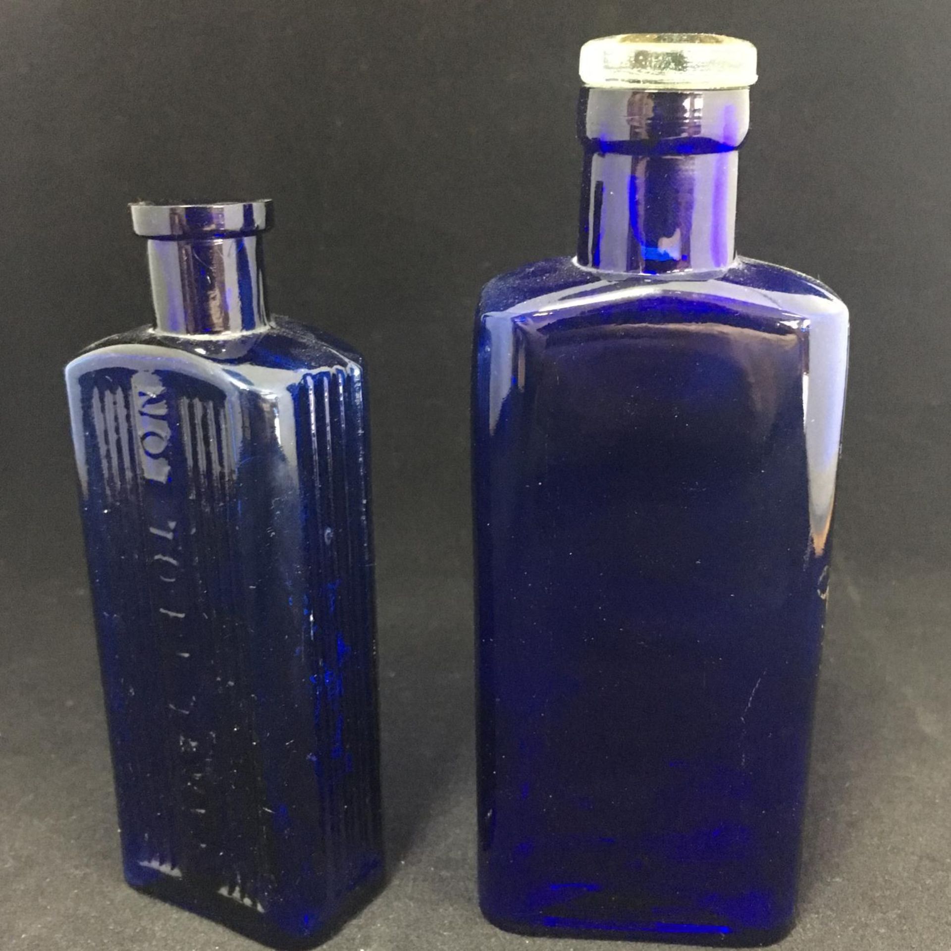 PAIR OF BLUE GLASS CHEMIST'S BOTTLES. One complete with original glass stopper. The hammer price
