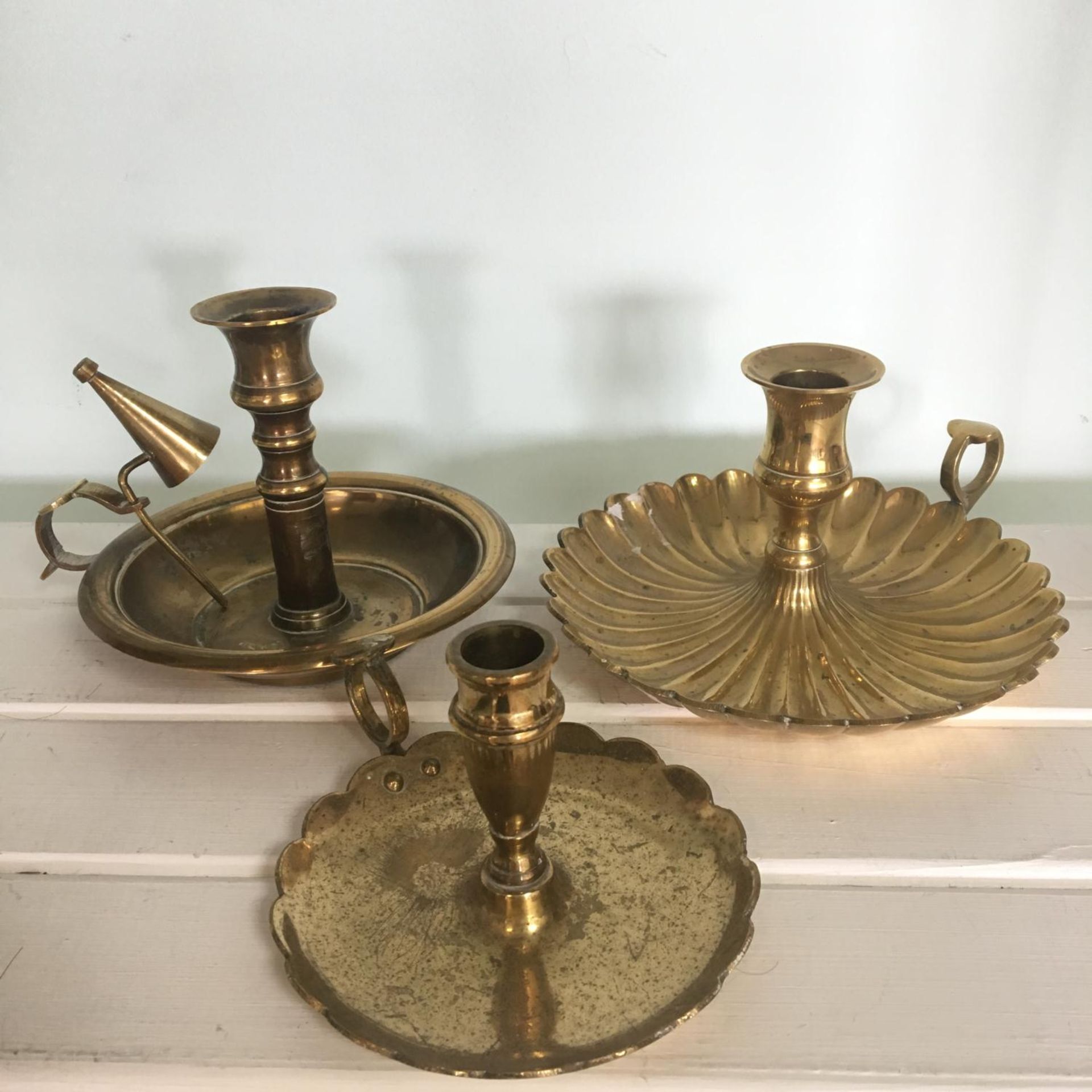 Group of three brass chambersticks of varying sizes, one with integral snuffer. Includes free UK