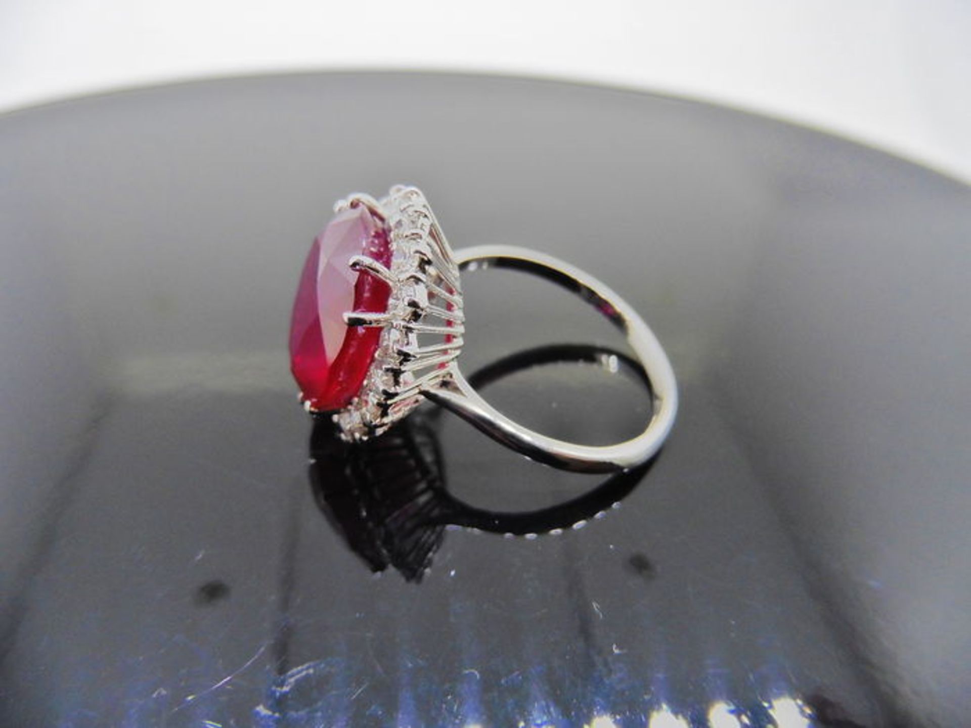 12ct ruby and diamond cluster ring. Oval cut ruby in the centre surrounded by brilliant cut - Image 3 of 4