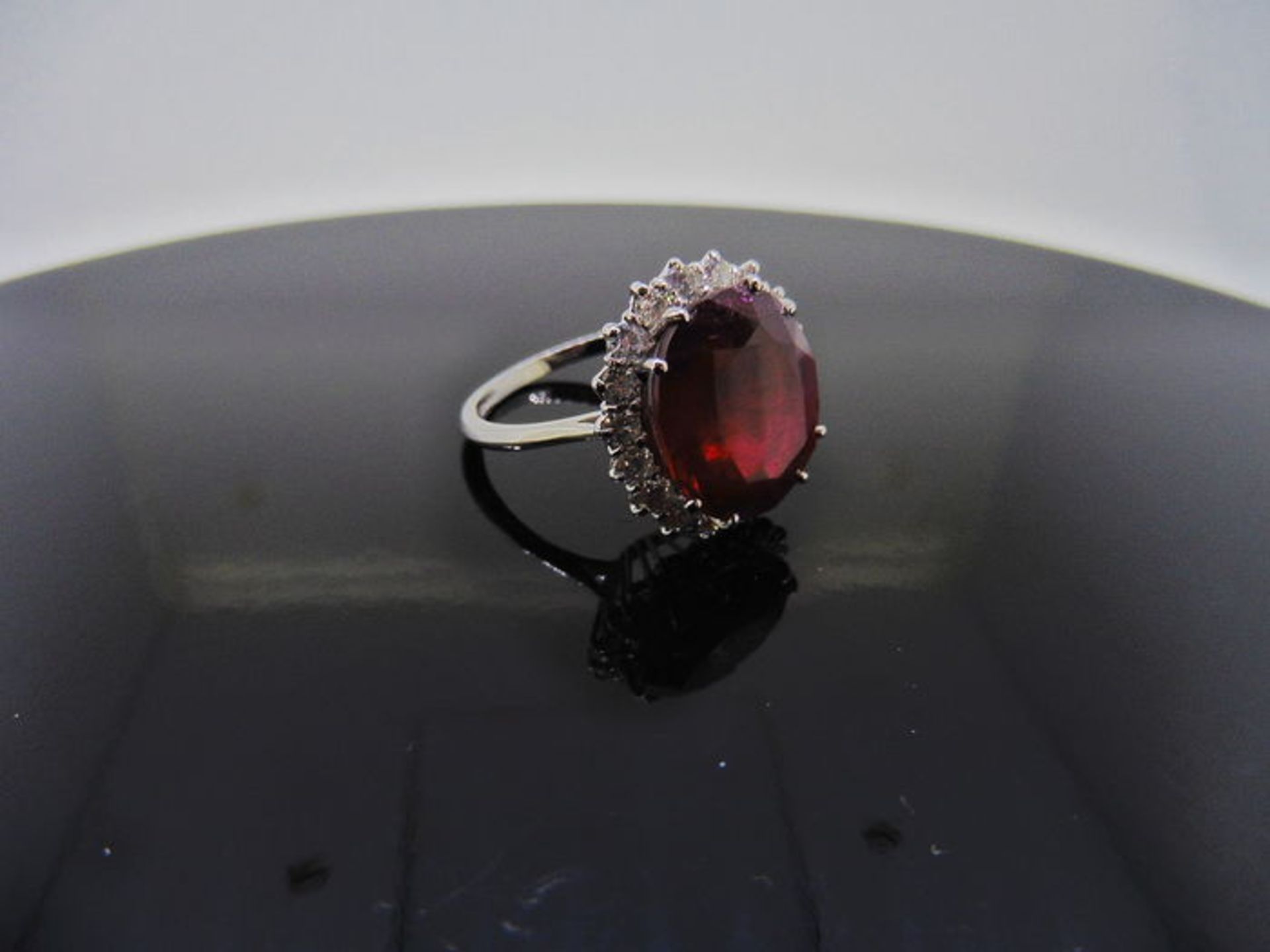 12ct ruby and diamond cluster ring. Oval cut ruby in the centre surrounded by brilliant cut - Image 2 of 4