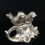 Vintage white metal salt and pepper set in the form of a pair of lovebirds, resting on a