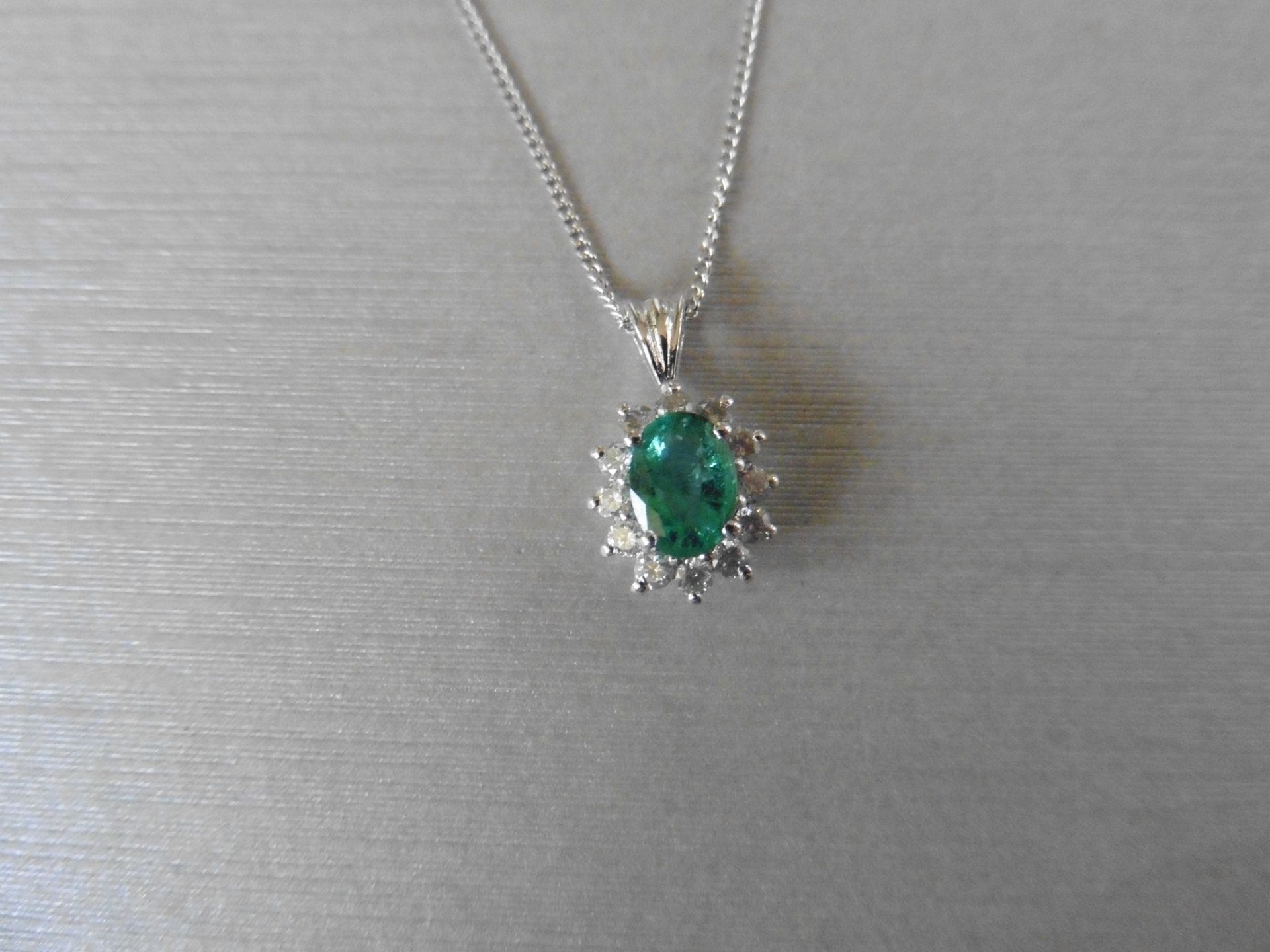 0.80ct emerald and diamond cluster style pendant.  Oval cut treated emerald with 12 small
