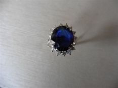 6ct sapphire and diamond cluster ring set in platinum. Oval cut colour treated ( glass filled ) sapp