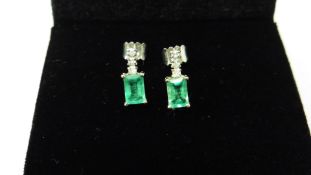 Emerald and diamond drop style earrings each set with an rectangular cut emerald, 6x4mm, weighing