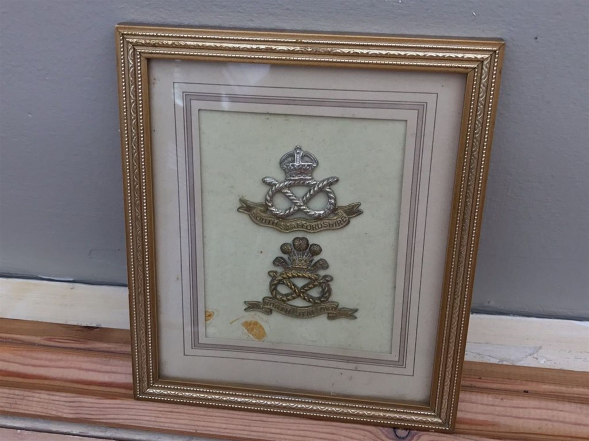 A quantity of The North/South Staffordshire and PayCorp cap badges Framed