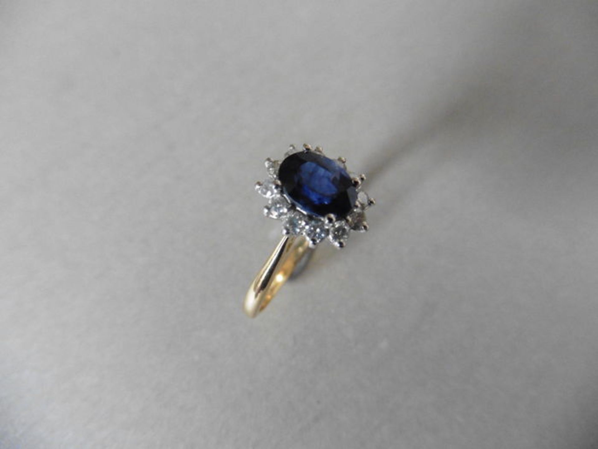 0.80ct sapphire and diamond cluster ring set with a oval cut (glass filled) sapphire which is