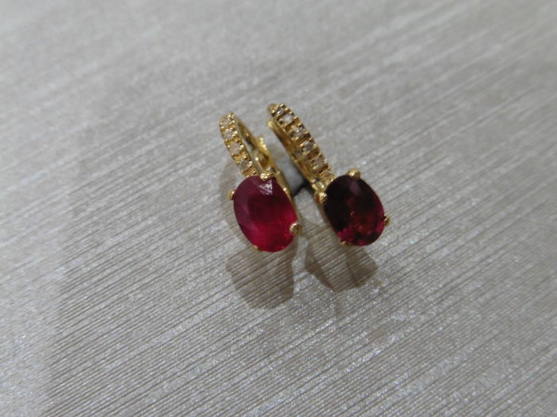 1.60ct Ruby and diamond hoop style earrings. Each is set with a 7x 5mm oval cut Ruby ( treated )